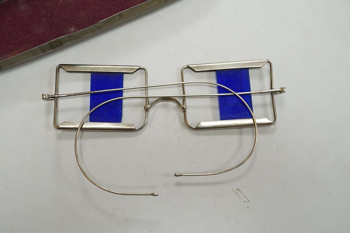 Two pairs of 19th century double D folding tinted spectacles, both cased, an unusual pair of green tinted pince nez with vulcanite side eye protectors, cased and a pair of optometrist ‘patent’ spectacles with sliding blu